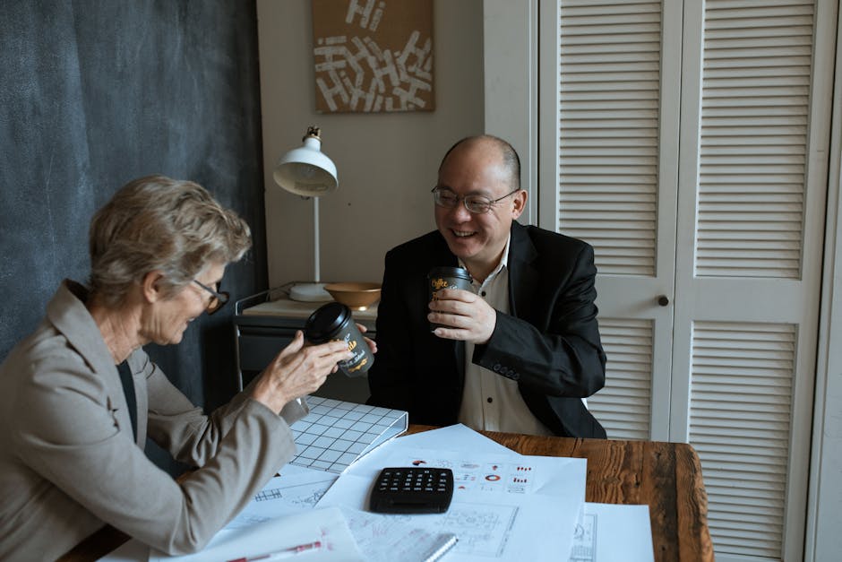 Business professionals sharing coffee and charts at an office table.
